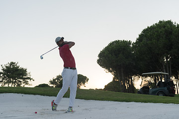 Image showing golfer hitting a sand bunker shot on sunset