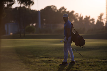 Image showing golfer  walking and carrying golf  bag at beautiful sunset