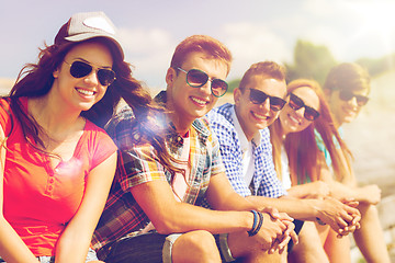 Image showing close up of smiling friends sitting on city street