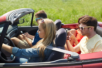 Image showing friends with smartphones driving in cabriolet car