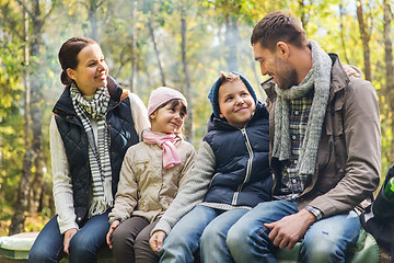Image showing happy family sitting on bench and talking at camp
