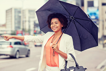 Image showing happy african woman with umbrella catching taxi