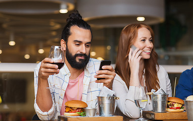 Image showing happy friends with smartphones at restaurant