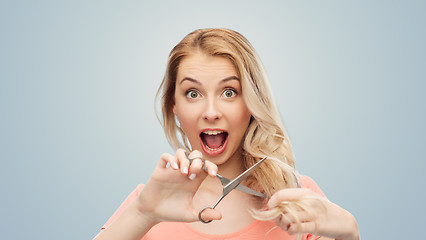 Image showing woman with scissors cutting ends of her hair