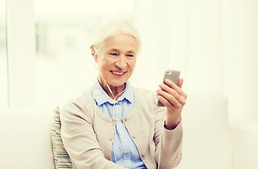 Image showing senior woman with smartphone and earphones at home