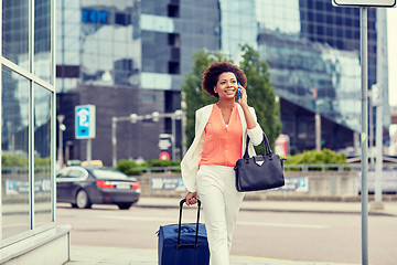 Image showing happy woman with travel bag calling on smartphone