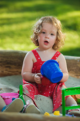 Image showing The little baby girl playing toys in sand