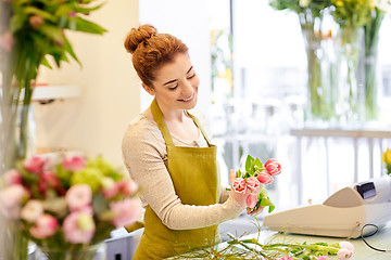 Image showing smiling florist woman making bunch at flower shop