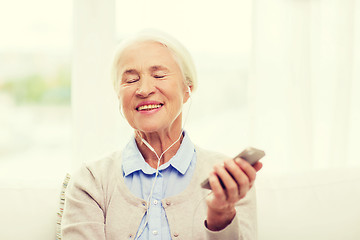 Image showing senior woman with smartphone and earphones at home