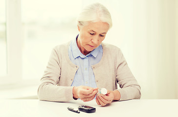 Image showing senior woman with glucometer checking blood sugar