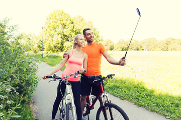 Image showing couple with bicycle and smartphone selfie stick