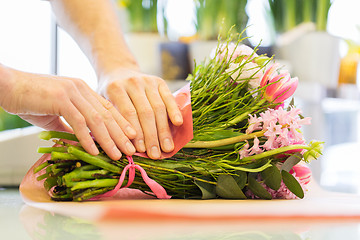 Image showing florist wrapping flowers in paper at flower shop