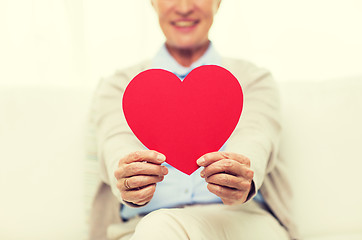 Image showing close up of senior woman with red heart at home