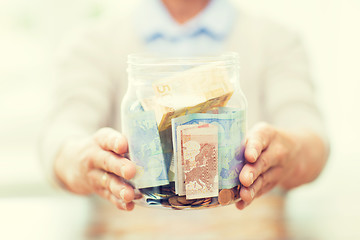 Image showing close up of senior woman with money in glass jar