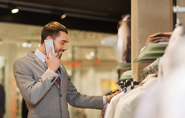 Image showing happy man calling on smartphone at clothing store