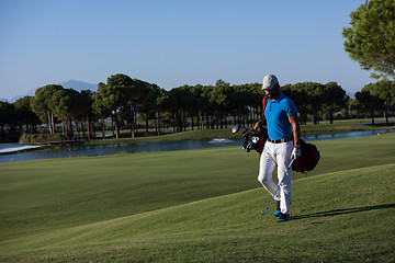 Image showing golf player walking and carrying bag