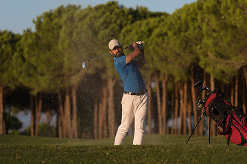 Image showing golfer hitting a sand bunker shot on sunset