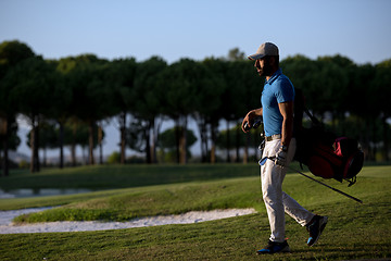 Image showing golfer  walking and carrying golf  bag at beautiful sunset