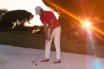 Image showing golfer hitting a sand bunker shot on sunset