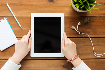 Image showing close up of woman with tablet pc on wooden table