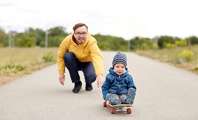 Image showing happy father and little son riding on skateboard