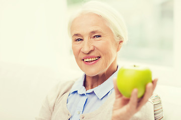 Image showing happy senior woman with green apple at home