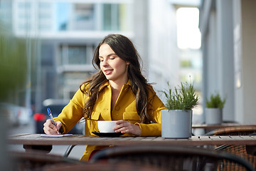 Image showing happy woman with notebook drinking cocoa at cafe