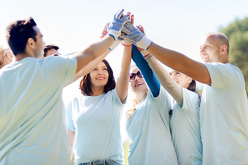 Image showing group of volunteers making high five in park