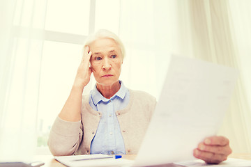 Image showing senior woman with papers and calculator at home