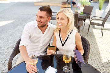 Image showing happy couple with wallet paying bill at restaurant