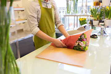 Image showing florist wrapping flowers in paper at flower shop