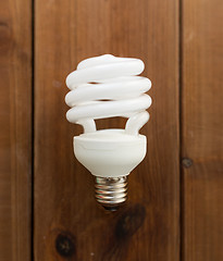 Image showing close up of energy saving lighting bulb on wood