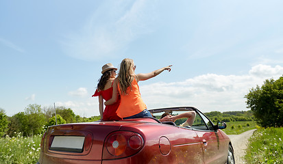 Image showing happy friends driving in cabriolet car at country