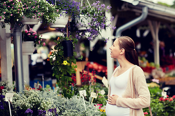 Image showing pregnant woman choosing flowers at street market