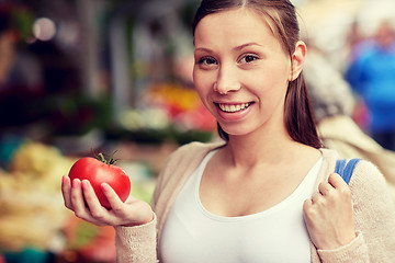 Image showing happy woman holding tomato at street market