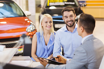 Image showing happy couple with car dealer in auto show or salon