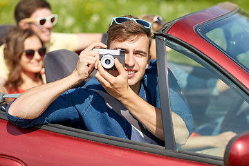 Image showing happy friends with camera driving in cabriolet car