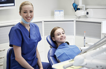 Image showing happy female dentist with patient girl at clinic