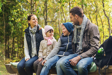 Image showing happy family sitting on bench and talking at camp
