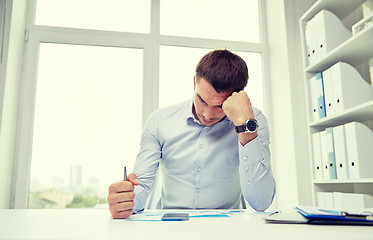 Image showing stressed businessman with papers in office