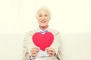 Image showing happy smiling senior woman with red heart at home