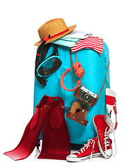 Image showing The blue suitcase, sneakers, clothing, hat, and retro camera on white background.