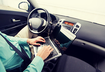 Image showing close up of young man with laptop driving car