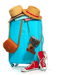 Image showing The blue suitcase, sneakers, clothing, hat, and retro camera on white background.