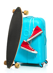 Image showing The blue suitcase, sneakers, skateboard on white background.