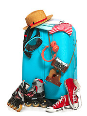 Image showing The blue suitcase, sneakers, clothing, hat, and retro camera on white background.