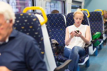 Image showing Woman using mobile phone while travelling by train.