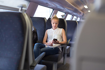 Image showing Woman using mobile phone while travelling by train.