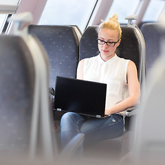 Image showing Woman travelling by train working on laptop.