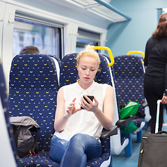 Image showing Woman using mobile phone while travelling by train.